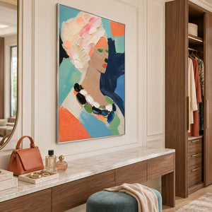 Colorful portrait painting of a woman with textured pale hair and a beaded necklace in a silver frame above a dressing vanity.