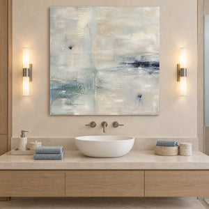 Square neutral abstract painting with ivory, pale aqua, and blue-gray marks without an outer frame beside a bathroom vanity.