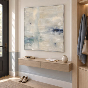 Square neutral abstract painting with ivory, pale aqua, and blue-gray marks in a silver frame in an entryway.