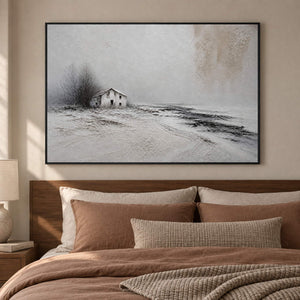 Winter landscape painting with a small house and dark trees beyond a snowy field in a black frame in a bedroom.