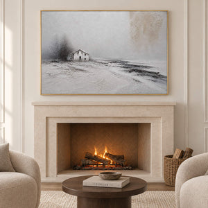 Winter landscape painting with a small house and dark trees beyond a snowy field in a gold frame in a seating area beside a fireplace.