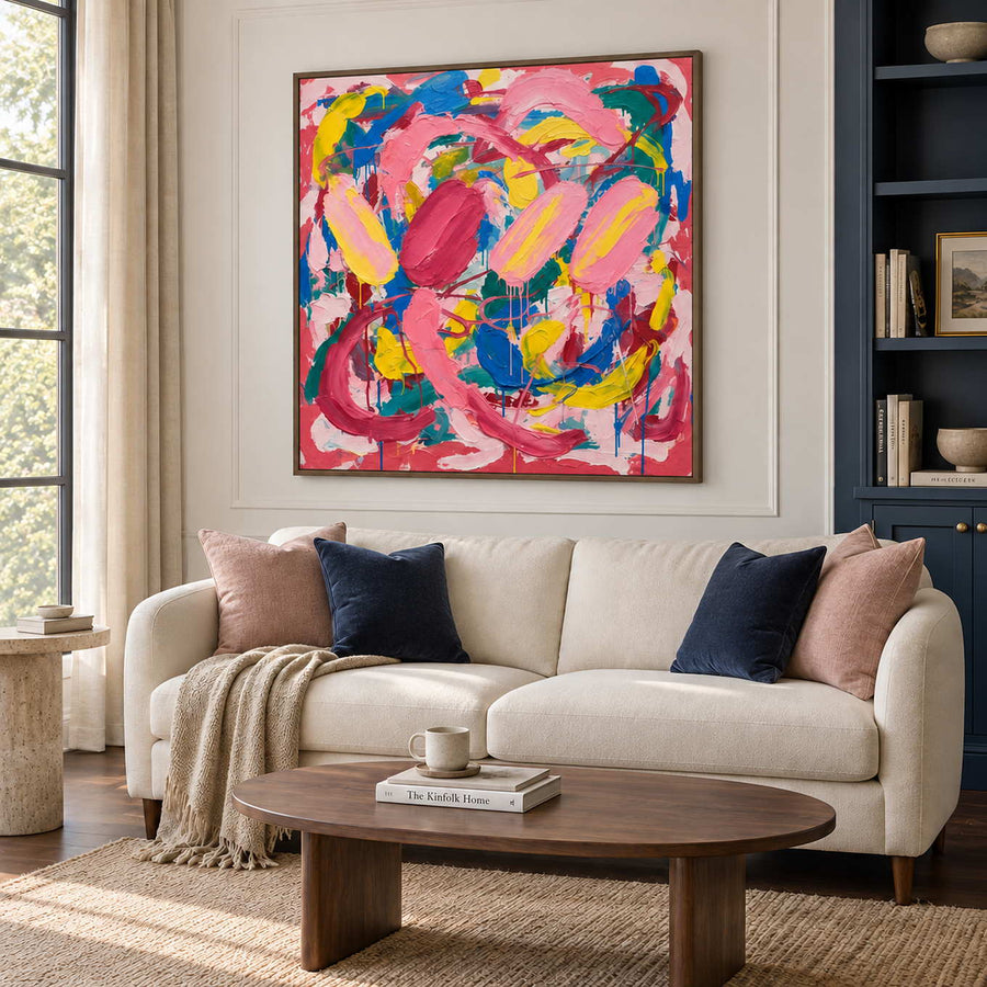 In Full Swing in a brown wood frame above a cream sofa with navy and blush cushions in a bright living room.