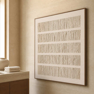 Wood framed pale ridged artwork beside a stone vanity in a bathroom dry area.