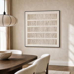 Black framed pale textured artwork above a wooden dining table with cream chairs.