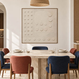 Warm white textured wall art with raised circles and quiet geometry, displayed in a dining room in a brown wood frame.