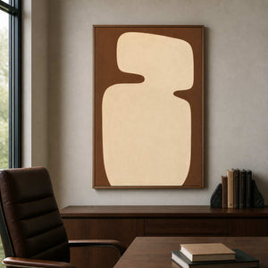 Wood framed rounded cream artwork overlooking a leather chair and desk in an office.