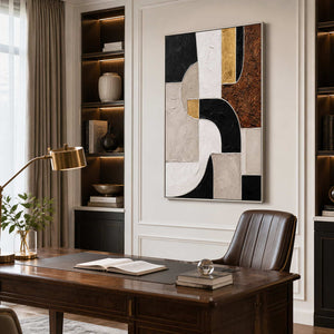 Silver framed geometric artwork above a wooden desk with a brown leather chair.