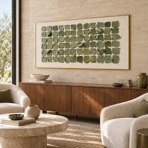 Keeping a Little Spring in a gold frame above a wood sideboard beside rounded cream chairs in a commercial lobby.