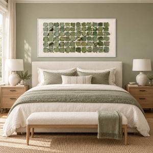 Keeping a Little Spring in a white frame above a cream bed with sage bedding and a green throw on the bench.