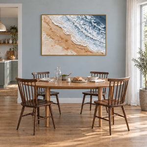 Kissing the Shore in a gold frame above a wood dining table against a blue-gray wall.