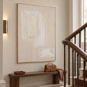 Ivory and blush relief painting with layered rectangles and a rough central panel in a gold frame on a stair landing.