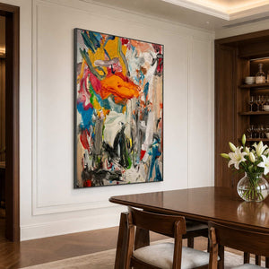 Black framed colorful abstract artwork beside a walnut dining table and white flowers.