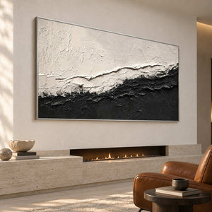 Wide monochrome artwork above a long narrow fireplace beside a brown armchair.