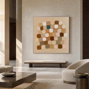 Silver framed square abstraction above a cushioned bench in a spacious neutral hall.