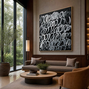 Gold framed white loop painting above lounge seating beside hotel lobby windows.