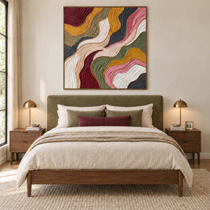 Love in Motion in a wood frame above an olive upholstered bed with cream bedding and a burgundy cushion.