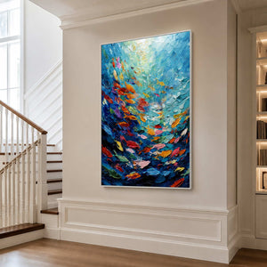 White framed colorful fish artwork beside a staircase in a bright cream hall.