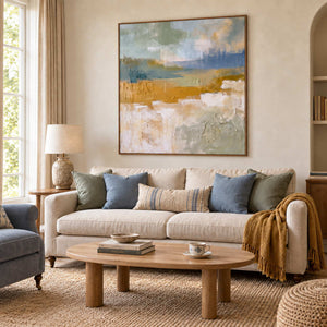 Meeting the Open Country in a wood frame above a cream sofa with blue and sage cushions and a mustard throw.