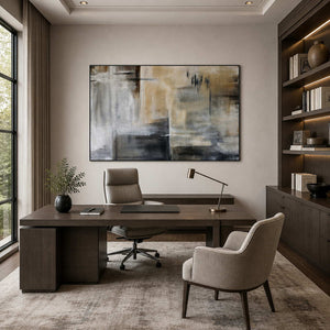 Black framed neutral abstract painting behind a broad office desk with dark shelving.
