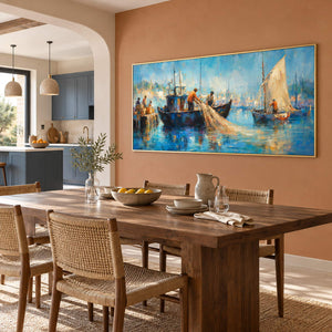 Hand-painted harbor scene with fishermen, sailboats, and luminous blue water, displayed in an open kitchen and dining area in a gold frame.