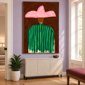 Pink-hat painting above a cream cabinet on a lavender wall beside a potted fern.