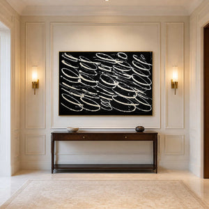 Gold framed looping abstract artwork above a wooden console between hallway sconces.