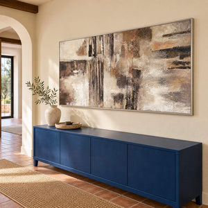 Hand-painted abstract wall art in ivory, taupe, umber, and charcoal, displayed in a hallway in a silver frame.