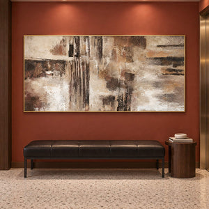 Hand-painted abstract wall art in ivory, taupe, umber, and charcoal, displayed in a hotel elevator lobby in a gold frame.