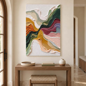 Tall abstract artwork above a wood console and woven stool beside an arched window.