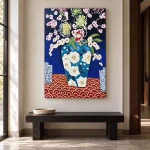 In an entryway above a console or bench, an artwork with no outer frame shows flowers in a blue floral-patterned vase above a red surface with repeated gold-colored arcs.