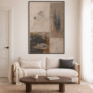 Weathered ivory and beige textures with gray blocks and dark marks in a black frame, displayed above a sofa in a living room.