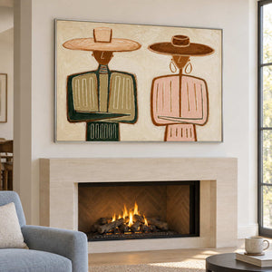 Paired portrait over a lit fireplace beside a blue chair.