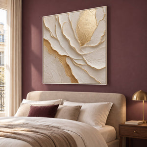 Hand-painted sculptural flower in layered ivory, white, and warm gold, displayed in a bedroom in a white frame.