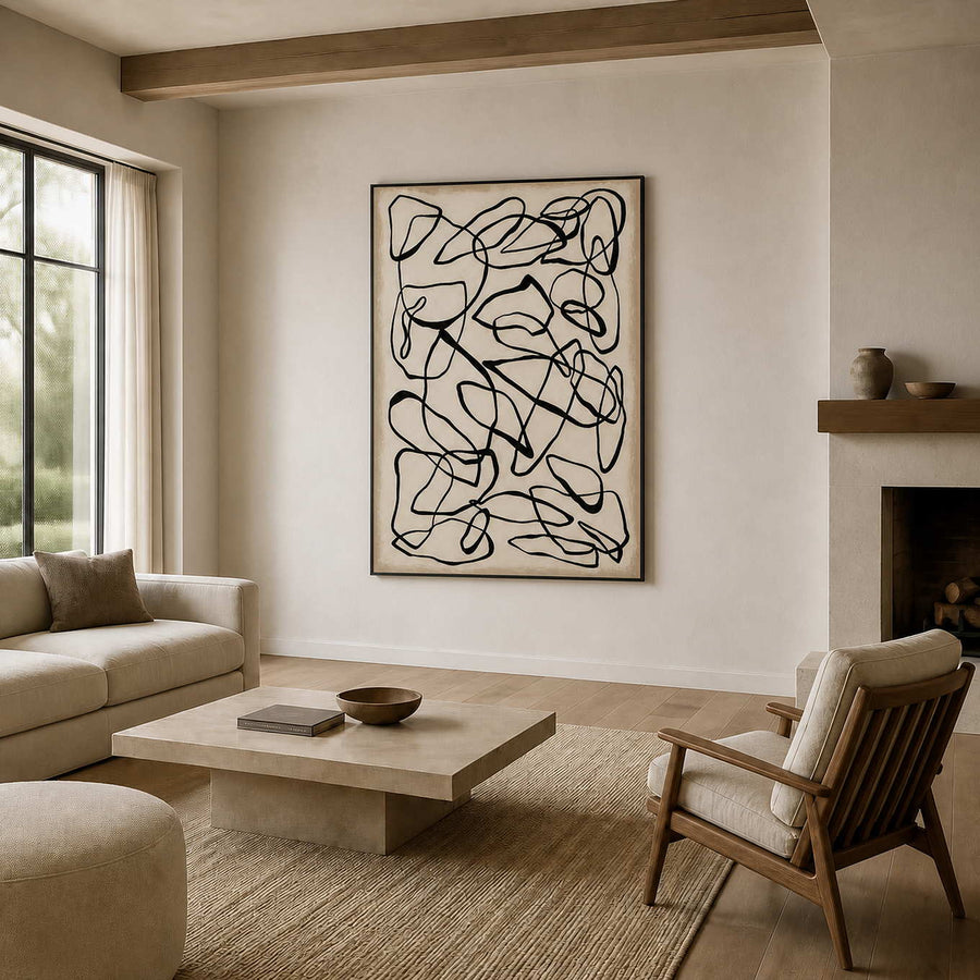 Black looping lines above a cream living room sofa beside a fireplace.