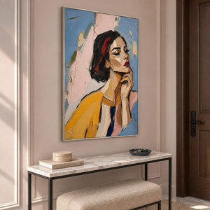Textured portrait of a dark-haired woman in mustard yellow in a silver frame in an entryway.