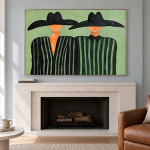 Paired portrait above a pale fireplace near a brown chair.