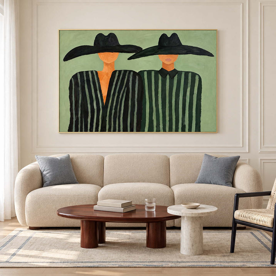 Green paired portrait above a rounded cream sofa.