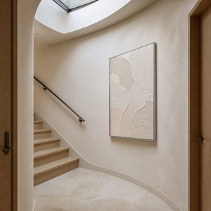 Vertical ivory relief artwork displayed beside a modern staircase.