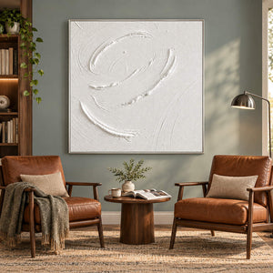 White minimalist relief painting with raised circular gestures in a silver frame in a reading room.