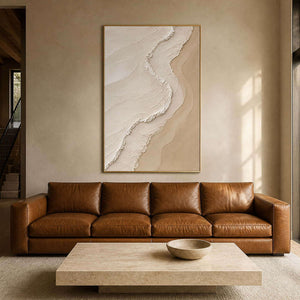 Textured neutral wall art above a caramel leather sofa in a warm living room.