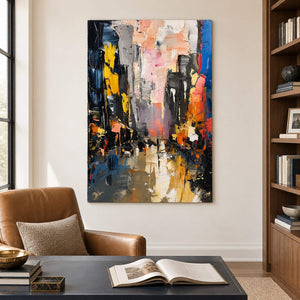 Textured rainy city street painting with yellow lights and dark buildings without an outer frame in a home office.