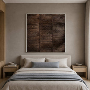 White framed brown textured painting above a bed with pale gray bedding.