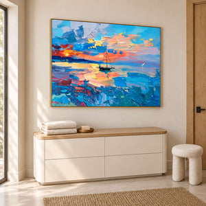 Angled sailboat painting above a white cabinet holding towels.