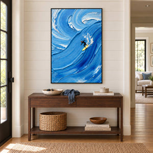 Riding the Wave in a black frame above a wood hallway console with a blue throw and woven basket.