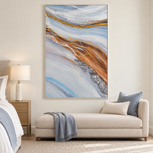 Pale blue-gray bands curving around ochre areas with fine white lines in an artwork with a white frame, displayed in a bedroom near the bed.