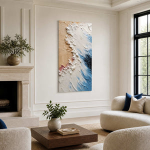 Frameless blue and white textured artwork between a fireplace and rounded cream living room seating.