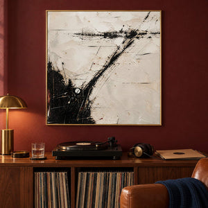 Ivory abstract painting with sweeping black marks and fine crossing lines in a gold frame in a music listening room.