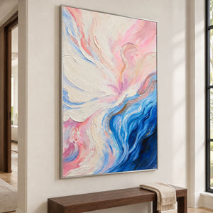 Artwork showing cream and pink folds flowing into deep blue curves at the lower right in a hallway above a bench, with a silver-colored frame.