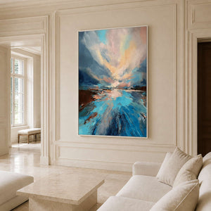 White framed blue landscape beside a cream sofa and pale stone coffee table.