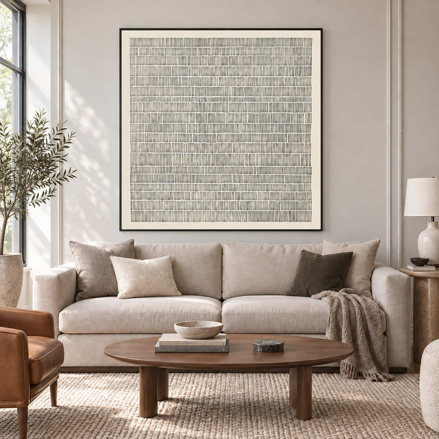 Slow and Lasting in a black frame above a cream sofa with taupe cushions and an oval wood coffee table.